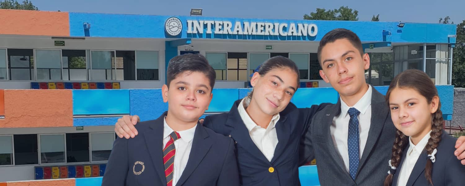 uatro alumnos y edificio de salones de Colegio Interamericano en el fondo.